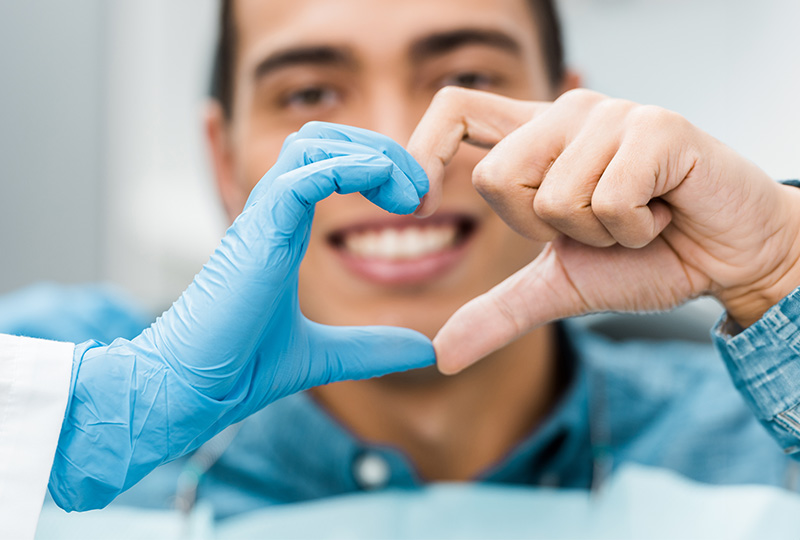 A group of five individuals, possibly dental professionals, in a dental office setting, celebrating with raised hands and thumbs up.